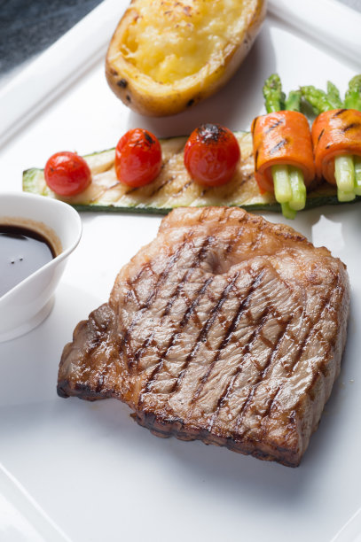 白盘子上的希达牛排配烤番茄、胡萝卜、黄瓜和芦笋图片下载