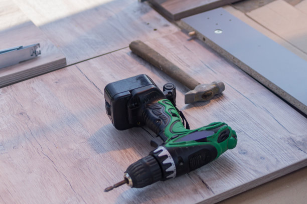 关闭电动螺丝刀。木匠的工作工具在地板上。图片下载