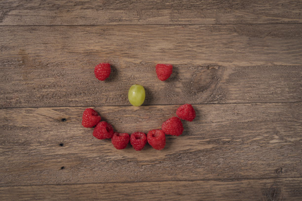 木桌上树莓葡萄笑脸图片下载