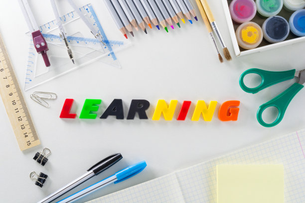 “学习”这个词来自白色背景上的多色塑料字母和学校文章。图片下载
