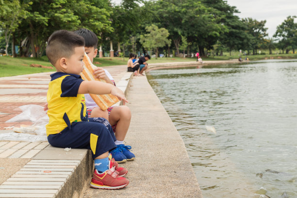 男孩坐在水边喂鱼图片下载