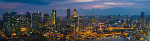 新加坡未来摩天大楼的城市景观在日落时照亮滨海湾全景图片下载