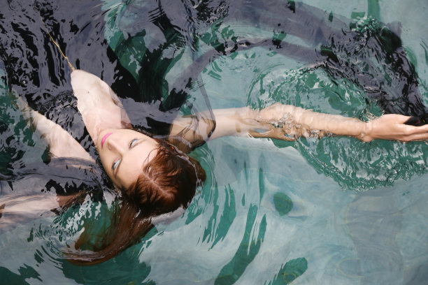 时尚照片的女人包裹在黑色透明织物在游泳池图片下载