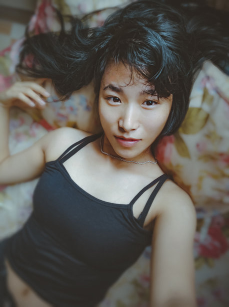 亚洲年轻女子躺在床上自拍。图片下载