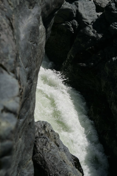 白色的泡沫在急流穿过黑色的岩石图片下载