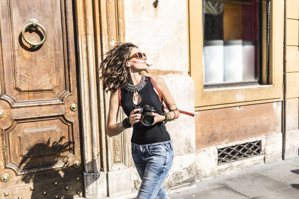 美丽的女人拿着相机走在街上图片下载
