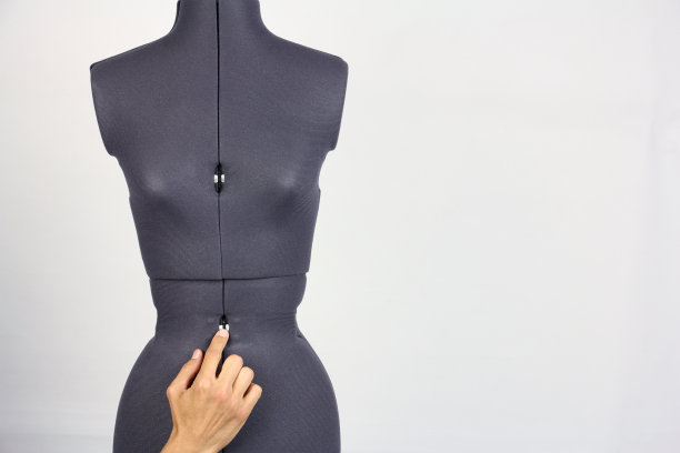 裁缝的手轻轻改变女性缝纫人体模型的臀部和腰部的宽度，灰色的背景，复制空间图片下载