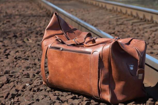 旅行袋放在铁路附近的石头上图片下载
