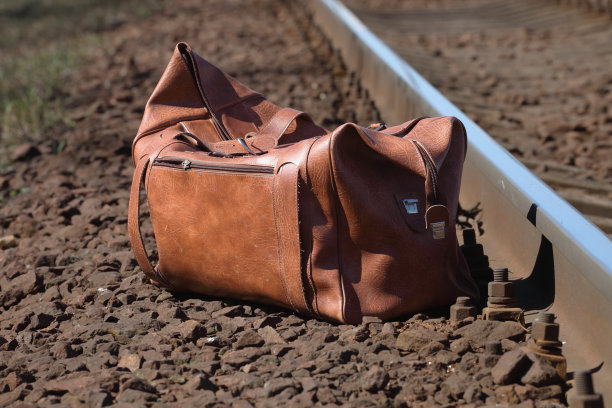 旅行袋放在铁路附近的石头上图片下载