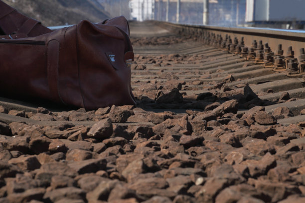 旅行袋放在铁路附近的石头上图片下载