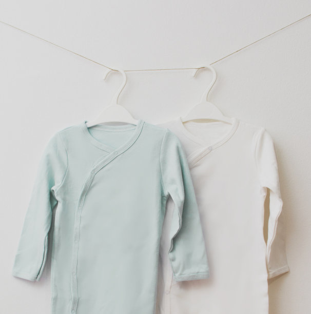 两件婴儿睡衣挂在衣架上。极简的概念，苍白的哑光颜色图片下载