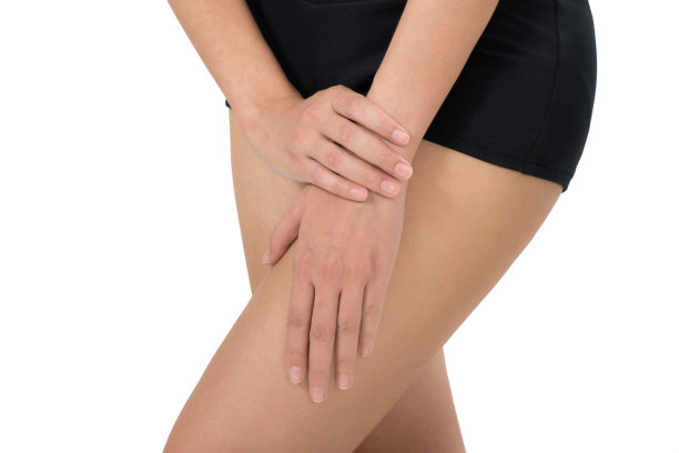 女人抱着她美丽健康的身体与按摩大腿疼痛的区域，孤立在白色的背景。图片下载