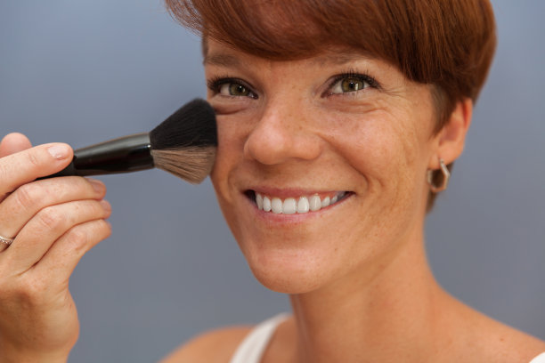 这位年轻女子用刷子在脸上擦粉图片下载