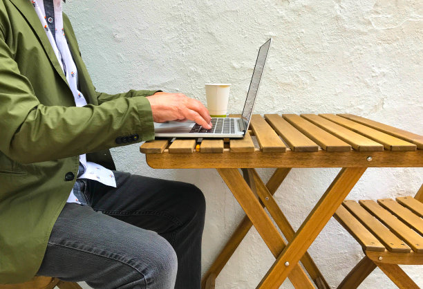 在户外小桌子上使用笔记本电脑的人图片下载
