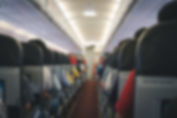 乘客坐在飞机上的座位上。飞机内部的过道。模糊的背景图片下载