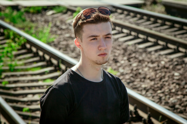 严肃英俊的年轻人站在铁路背景上的肖像图片下载