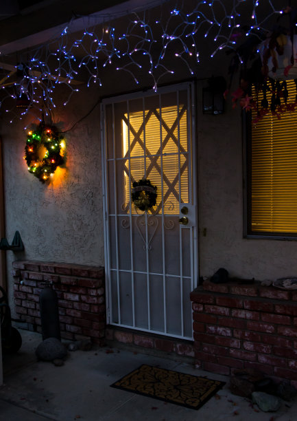 前门廊的节日灯和圣诞花环在晚上与发光的室内灯。图片下载