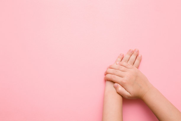 小孩的手放在淡粉色的桌子上。关心干净，整洁的孩子的身体皮肤。模型为积极的想法。空的地方，情绪化的文字，引用或语录。图片下载
