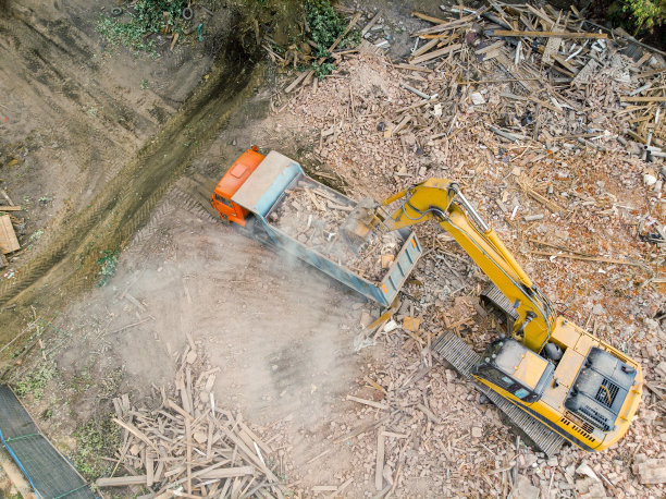 挖掘机正在用自卸卡车装载被毁建筑的残骸。航拍照片图片下载