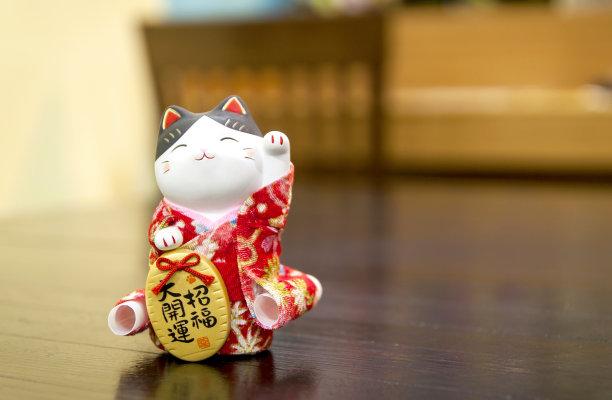选择性聚焦Maneki Neko，日本幸运猫，在一个木制的桌子上模糊的背景和文本输入复制空间。图片下载