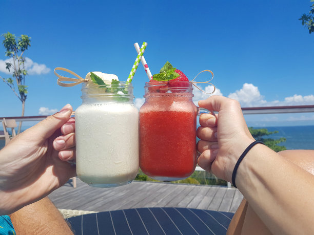 特写:旅客在放松的海边度假making a toast with smoothies。图片下载