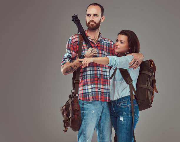 摄影棚里的男女游客背着背包和三脚架，在摄影棚里拥抱在一起。图片下载