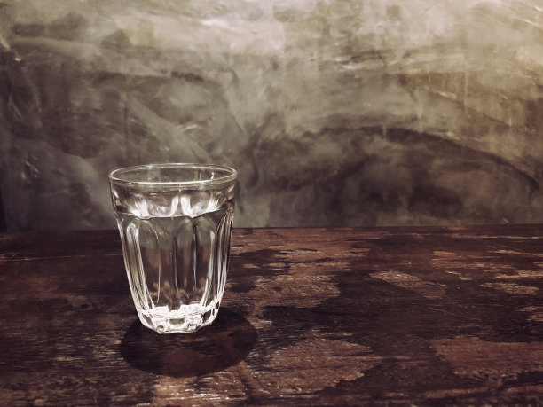 木桌上的一杯水以水泥为背景延伸出光影与copyspace图片下载