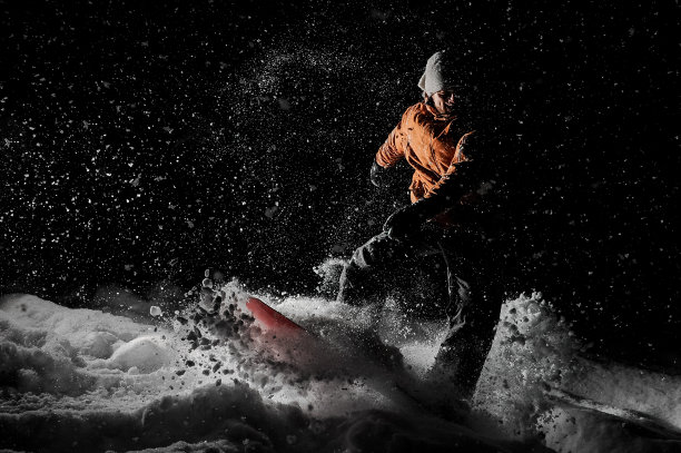 一个年轻人晚上在山区度假胜地玩滑雪板图片下载