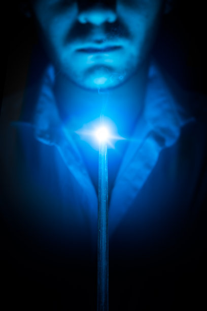 在黑暗的背景上拿着魔杖的巫师图片下载