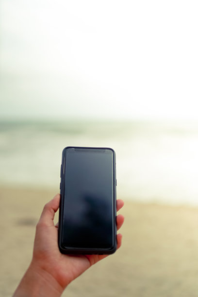 女人在夏季海滩前使用智能手机，阳光明媚图片下载