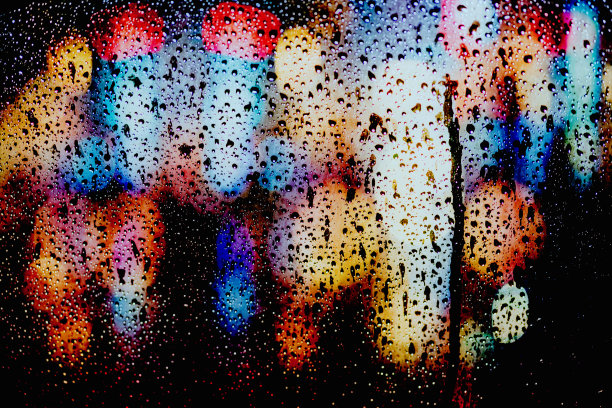 在城市的背景下，雨点落在车窗上。图片下载