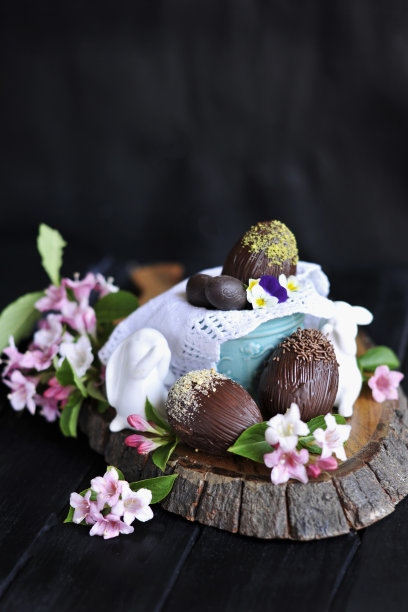 复活节糖果。家里做的巧克力。巧克力蛋。粉色的鲜花盛开。在黑色的背景上。黑暗的照片,图片下载