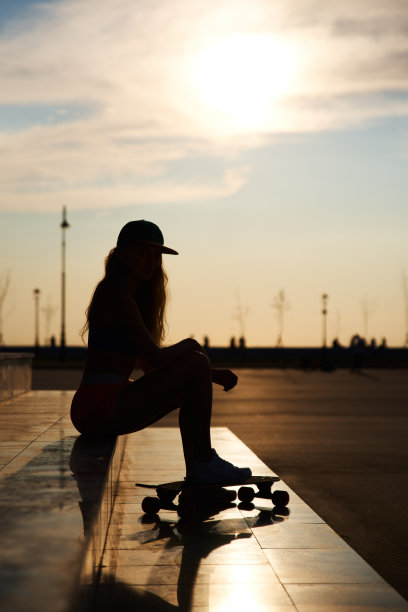 戴帽子的女超人和隆巴顿的剪影。美丽的垂直照片的潮人在日落。图片下载