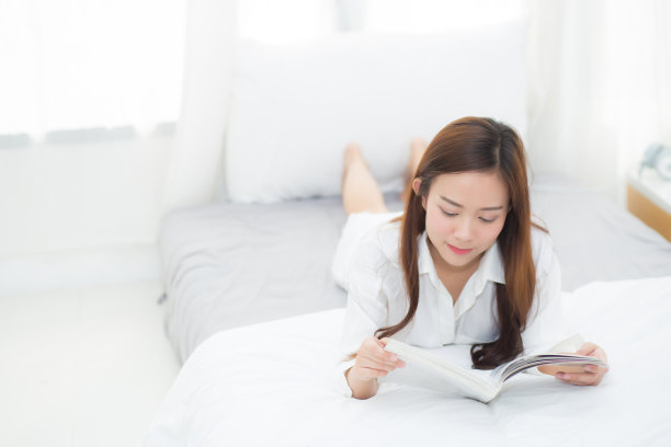 美丽的肖像年轻的亚洲女人放松躺在卧室看书早上在家里，女孩研究文学，教育和生活理念。图片下载