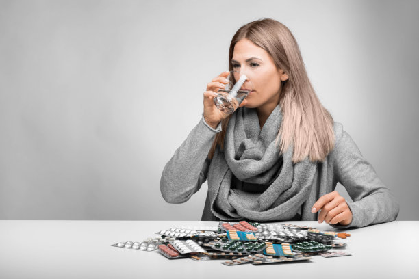 年轻的金发女人坐在许多药丸前图片下载