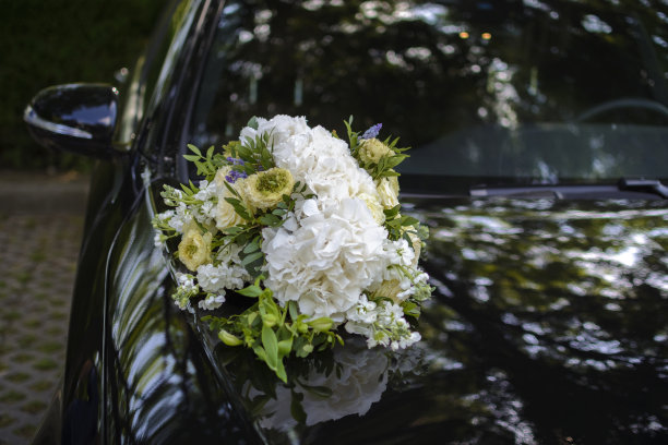 婚礼花束放在一辆黑色轿车的车顶。图片下载