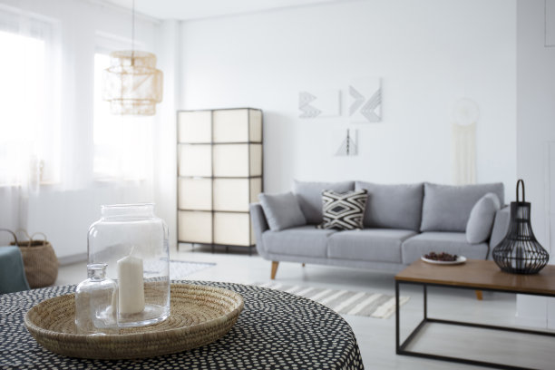 在宽敞的白色客厅里，桌上放着蜡烛，灰色沙发上有图案靠垫。真实的照片图片下载