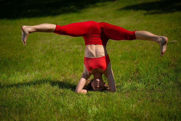 年轻迷人的女人在户外练习瑜伽。这个女孩做了一个倒立素材图片