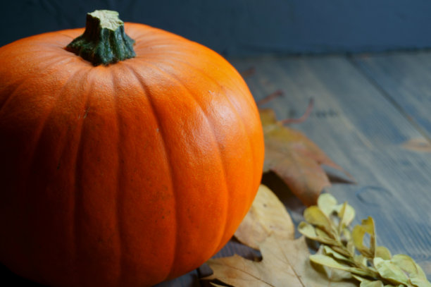 木桌上放着橙色的南瓜和秋天的叶子图片下载