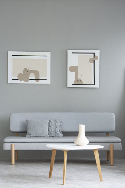 木质的白色桌子在灰色沙发前面，在最小的客厅内饰有绘画。真实的照片图片下载