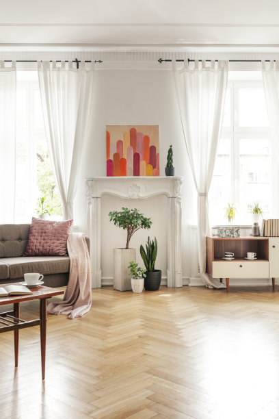 木质桌子和米色沙发在宽敞的客厅内饰海报和植物。真实的照片图片下载