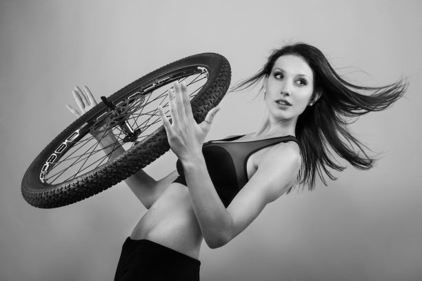 年轻女子扶着车轮靠墙图片下载