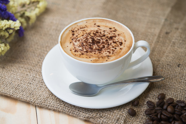 紧靠在木桌上的热咖啡杯和一些咖啡豆。图片下载