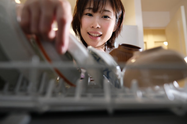家庭主妇把盘子放进洗碗机图片下载