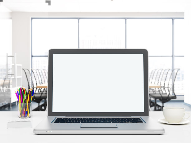 办公室内部的桌子上放着空白屏幕的笔记本电脑图片下载