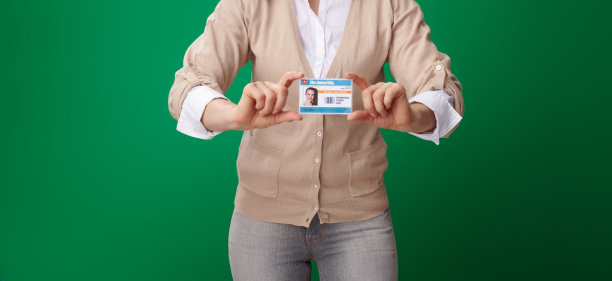 女学生在绿色背景上展示孤立的学生证图片下载