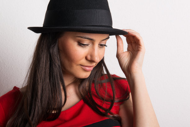 一个在工作室里戴着黑帽子的年轻漂亮女人的特写。图片下载