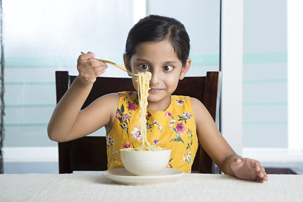可爱的小女孩在家里吃通心粉和奶酪。-股票图片图片下载