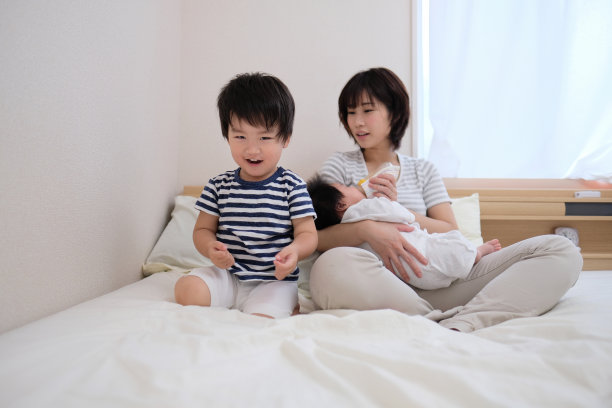 母亲，婴儿和幼儿坐在床上图片下载