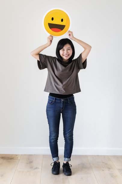 快乐的亚洲女人拿着一个笑脸表情图片下载